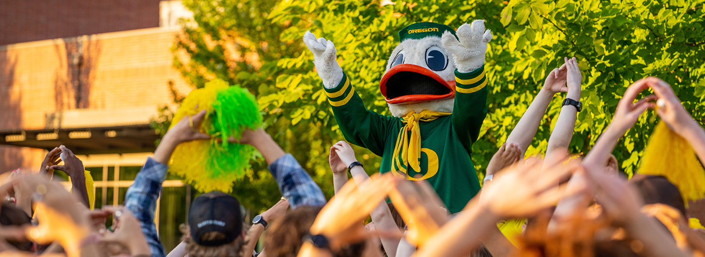 Cheer with the Duck Oregon Duck mascot leading a cheer in front of a crowd of students